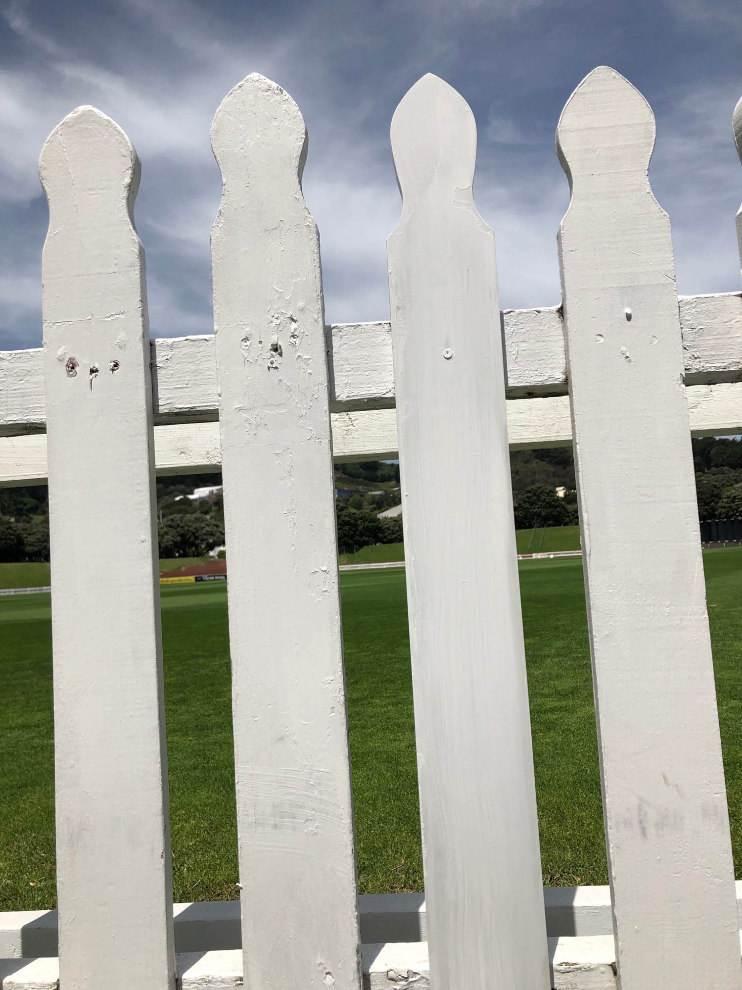 A photograph of a low wooden fence painted white.