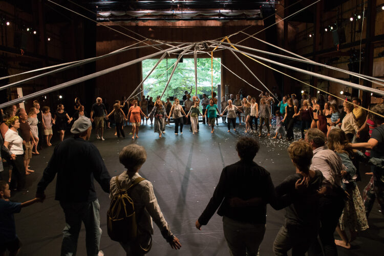 People in a circle inside a large performance space.