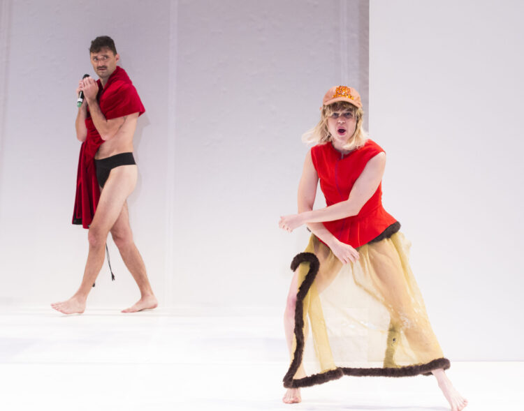Two people on a bright white stage wearing red.