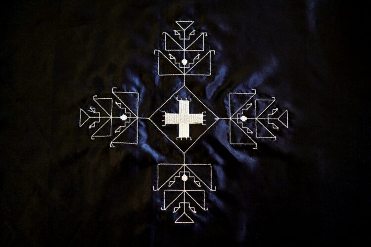 Dark blue satin fabric with silver thread, arranged in a geometric motif.