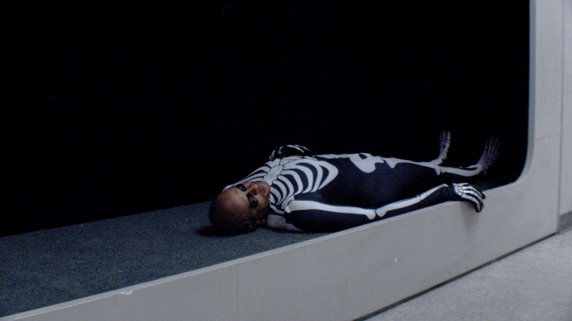 A person in a skeleton costume lying down.