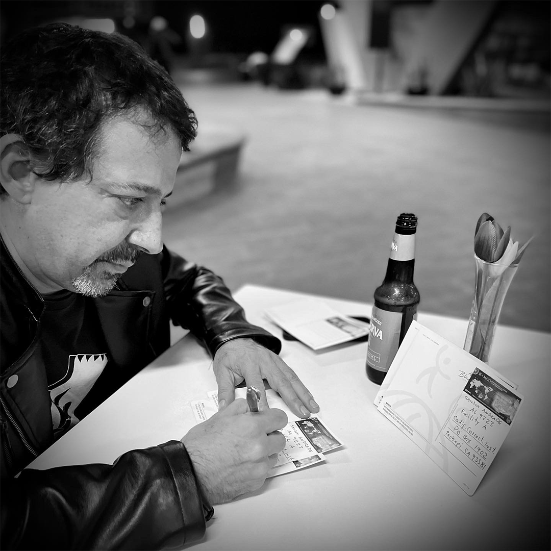 A man at a table writing a postcard.