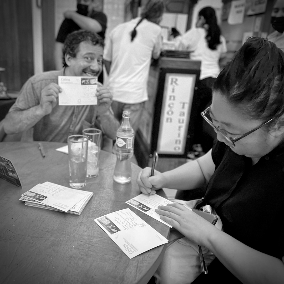 People writing postcards at a table.