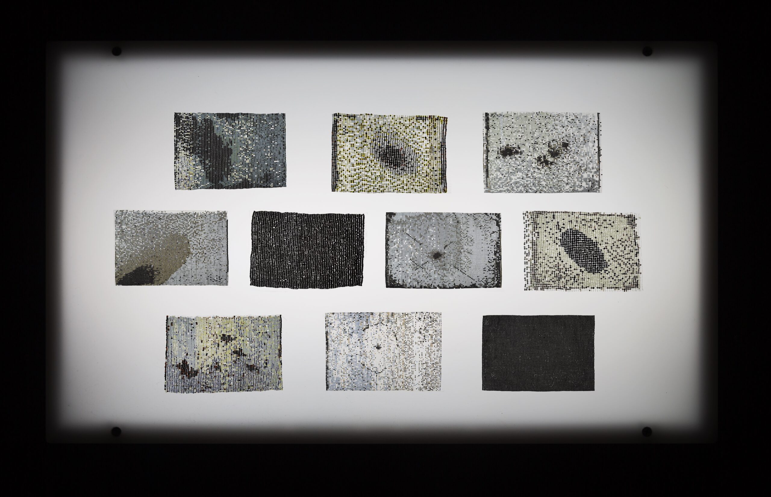 Ten beaded works on a lightbox.