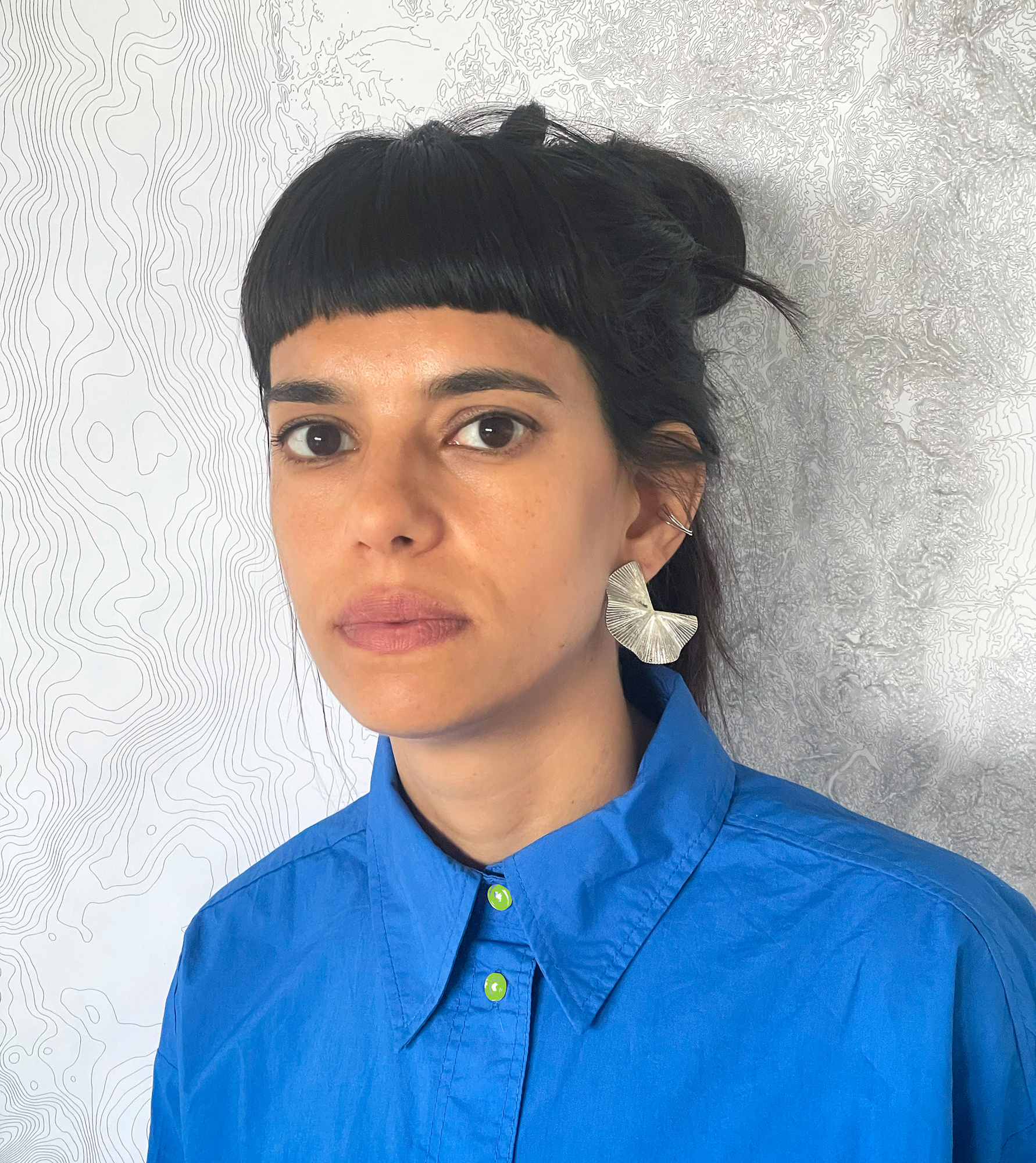 Paula Gaetano Adi looking at camera with a blue shirt.