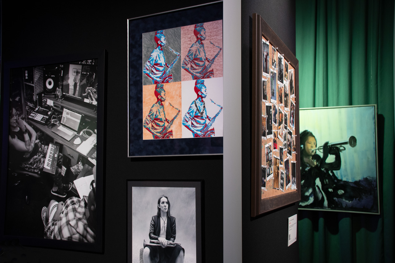 photo of exhibit, including “Conseulo en B-639” (Kokayi), Jazzwoman” (Tracy Love and Terri Lyne Carrington), “Rest: Space Between the Notes” (Tracy Love), corkboard “Road Work”, and Joe Diggs painting “Valaida Snow” (from right to left)