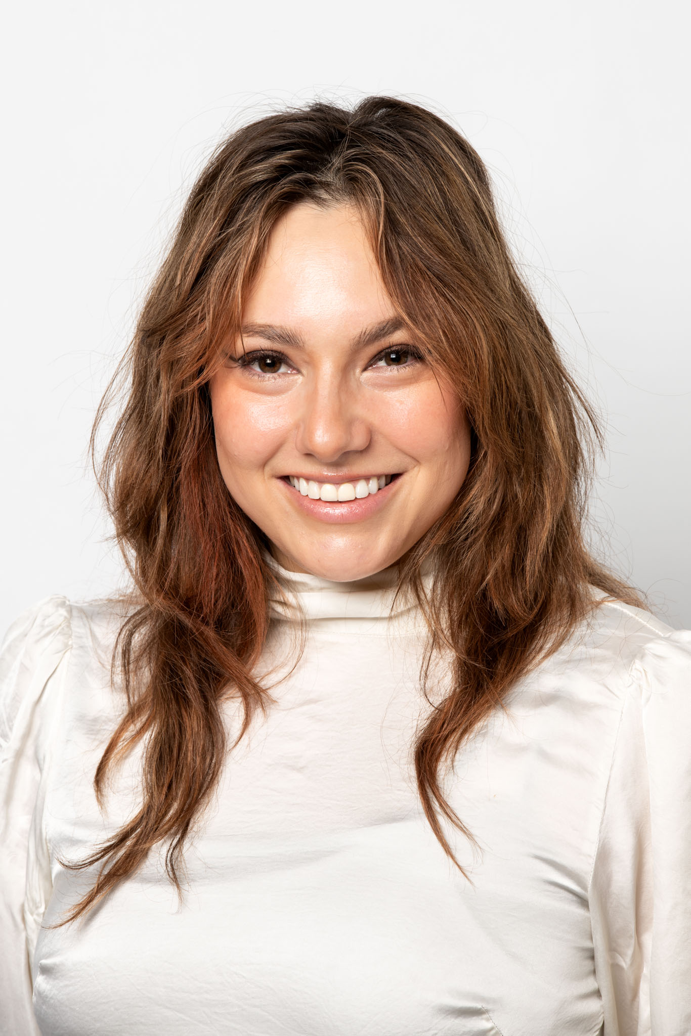 Image of the artist Kite. Image of a female person smiling, wearing a white turtleneck and placed against a white backdrop.
