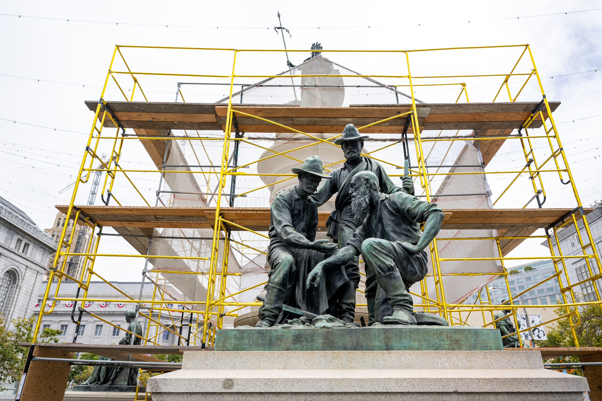 A work by Kaleb Duarte and a team of artists titled Embassy of the Refugee near Civic Center Plaza in San Francisco on July 6, 2026, uses scaffolding, plywood, and netting to cover the Pioneer Monument and highlight the experiences of undocumented migrants.