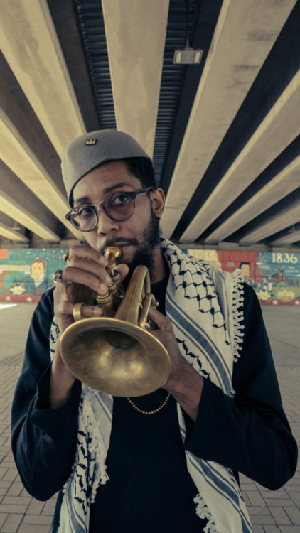 Jawwaad playing trumpet in front of a Houston mural on the eve of a video release.