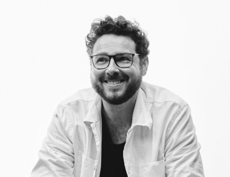 Christopher Marianetti in a white shirt sitting and smiling.