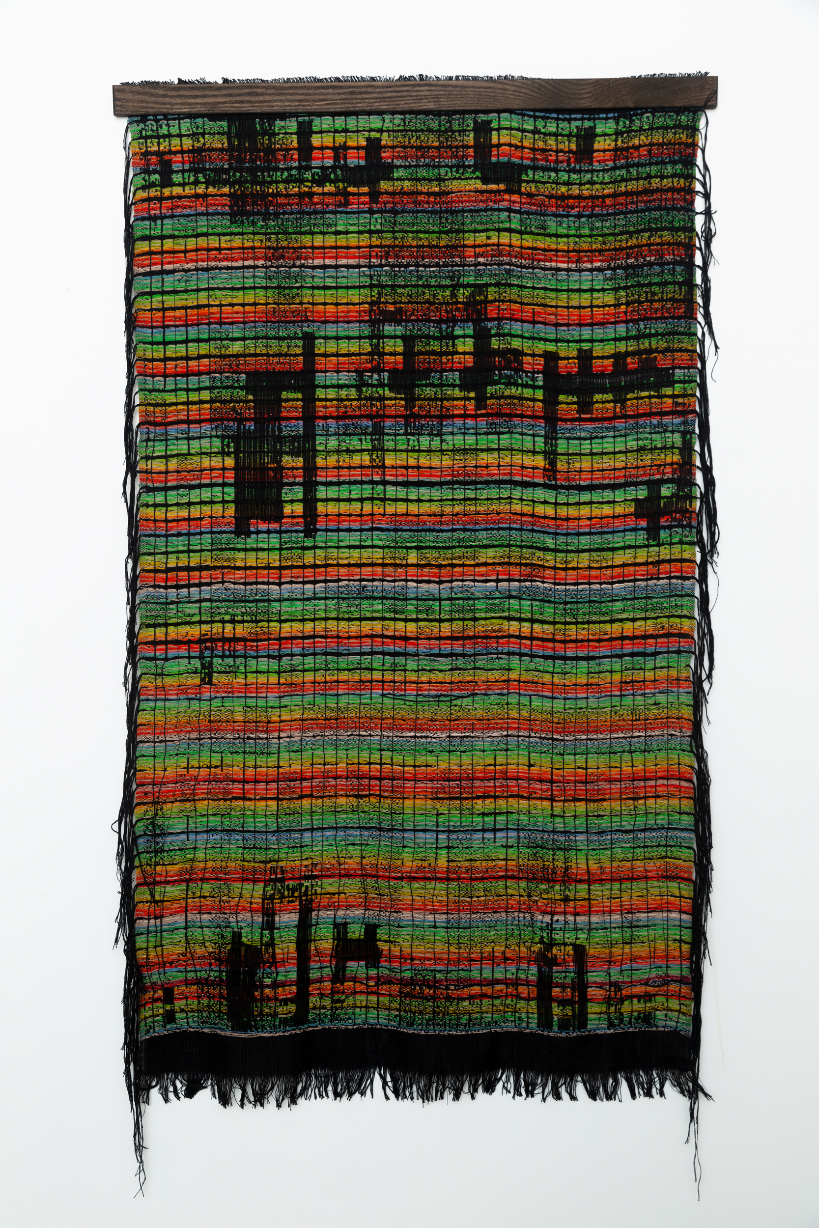 A colorful woven textile with fringe.