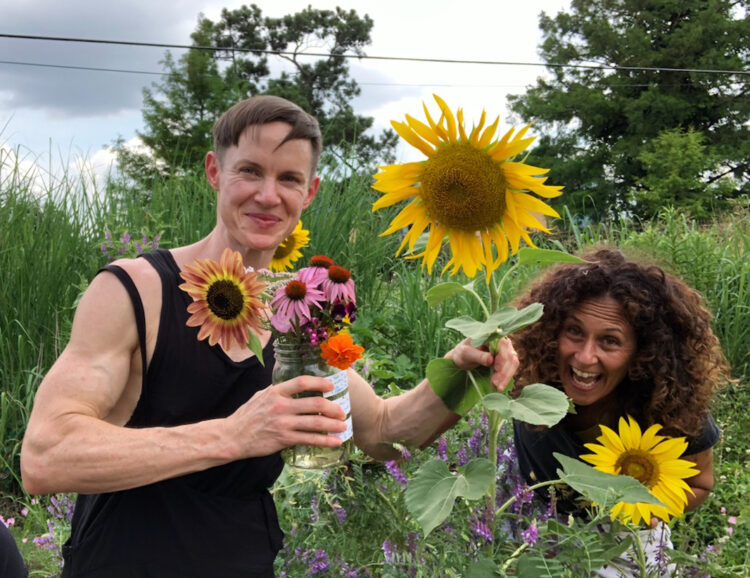 Two people standing in a field holding flowers.