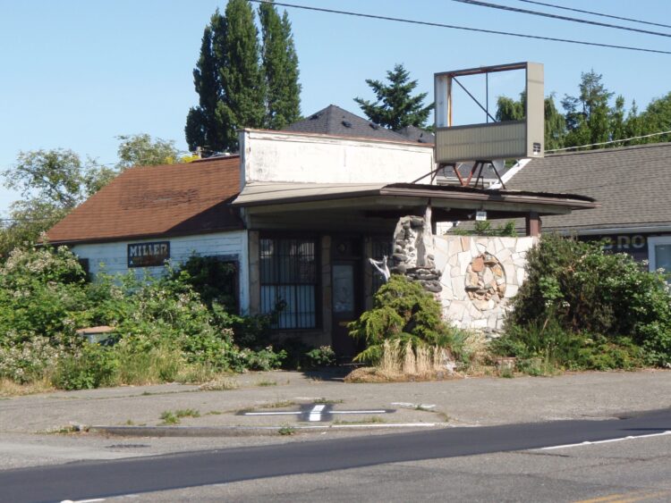 An abandoned gas station overgrown with vines.