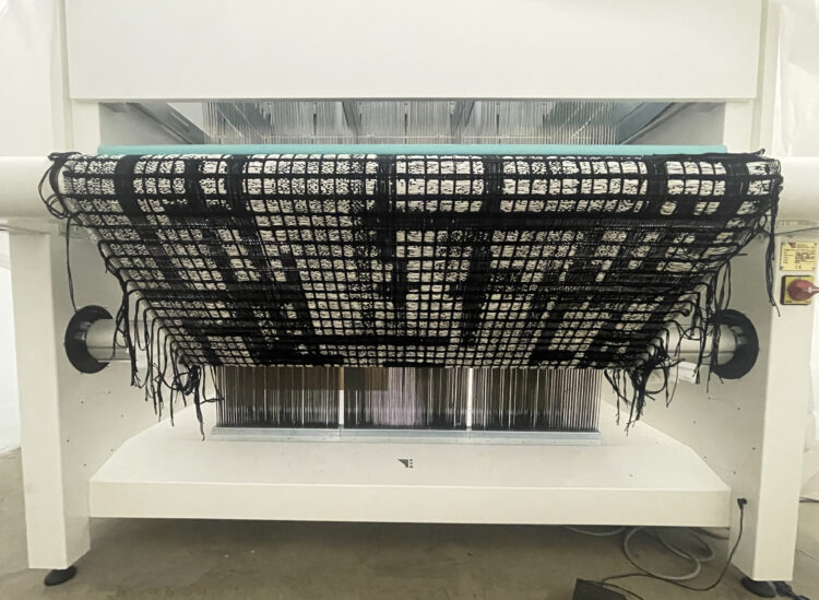 A large loom with a black and white weaving on it.